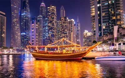 Stunning night view of the Dubai Marina skyline and a traditional dhow boat, representing the wide local areas served by the best movers and packers in Dubai.
