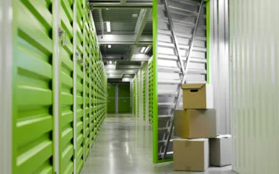 Indoor view of a clean, secure, climate-controlled storage facility hallway with green metal units. Dependable storage services in Fujairah by dubaicitymovers.ae.