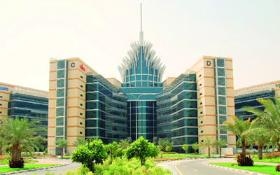 Large, modern, glass-fronted office building in a green business park, representing Dubai Silicon Oasis (DSO). Expert residential and commercial movers serving Silicon Oasis by dubaicitymovers.ae.